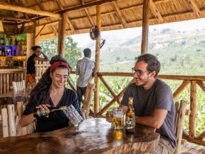 a man and a woman sitting at a table with beer at Nyanja View Resort in Fort Portal