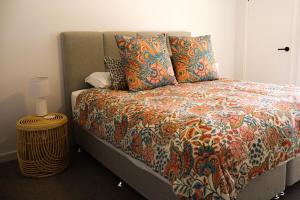 een bed met een kleurrijke deken en kussens erop bij Beach Street - LJHooker Yamba in Yamba +10 foto's