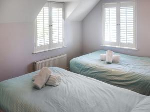 Dos camas en un dormitorio con dos ventanas. en Tideglass, en Penally