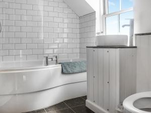 Un baño blanco con bañera y inodoro. en Tideglass, en Penally 3 fotos más