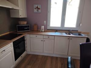 a kitchen with white cabinets and a sink and a window at Au sable fin in Grand-Fort-Philippe