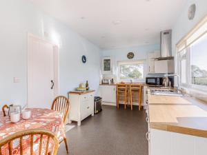 una cocina con armarios blancos y una mesa con mesa en Mark Farmhouse, en Bradwell on Sea 13 fotos más