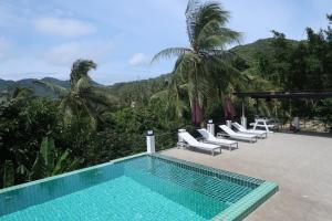 a swimming pool with white lounge chairs next to a resort at Villa Seaview Garden in Ko Tao