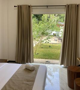 een slaapkamer met een bed en een groot raam bij Ocean Edge Holiday Resorts in Hiriketiya +27 foto's