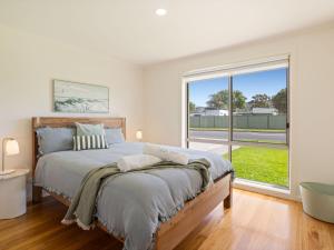 een slaapkamer met een groot bed en een groot raam bij Baravi Breeze Retreat in Safety Beach