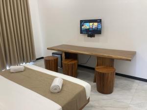 a room with two beds and a table with a television at Ocean Edge Holiday Resorts in Hiriketiya