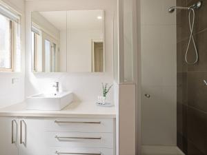 een witte badkamer met een wastafel en een douche bij Baravi Breeze Retreat in Safety Beach +19 foto's