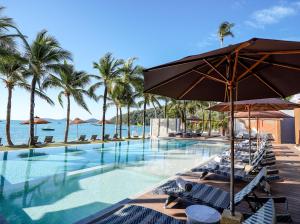 パナワビーチにあるBandara Pool Villas, Phuketの海のそばのスイミングプール(椅子、パラソル付)