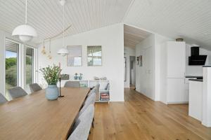 een eetkamer en keuken met witte muren en een houten tafel bij Newly Renovated Holiday Home With Aarhus Bay Views in Rønde