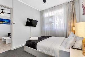 a white bedroom with a bed and a window at Walk to Beach And Cafes Near City And Airport in West Beach
