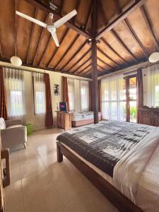 a bedroom with a large bed with a ceiling fan at Alamanda Villas, Family Villas, Pool & Local Tours in Yogyakarta
