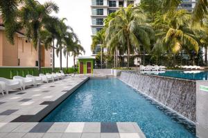 a pool with chairs and palm trees in a building at Acappella Suite Hotel, Shah Alam in Shah Alam
