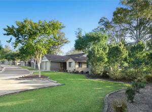 een huis met een tuin met groen gras en bomen bij 20 Min to Brisbane, Walk to Train, Modern 2BR in Goodna