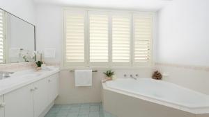 a white bathroom with a tub and a window at La Playa in Myola