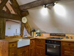 a kitchen with wooden cabinets and a stove top oven at Lees Farm Apartment in Walcot