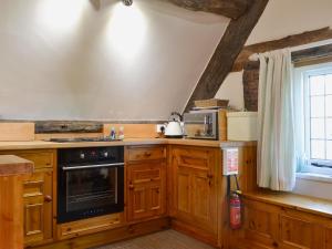 a kitchen with wooden cabinets and a stove top oven at Lees Farm Apartment in Walcot