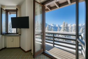 a room with a balcony with a view of the mountains at Appartamento Principino 24 Ski in Ski out - Happy Rentals in Sestriere