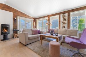 a living room with a couch and chairs and a fireplace at Luxury cabin with amazing views in Stryn