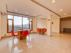 a large room with chairs and tables and windows at Omavya Hotel Manali in Jagatsukh