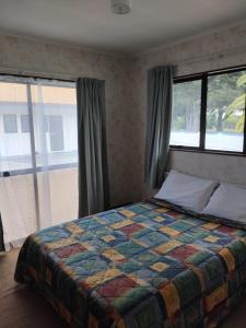 Un dormitorio con una cama con una colcha colorida y ventanas. en Napier Nest Motel, en Napier