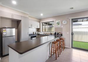 a kitchen with a counter and some stools in it at LIVING LUX Ballarat, Modern 2BR Home with Garden, Free Parking in Sebastopol
