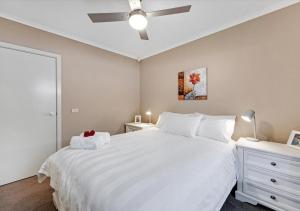 a bedroom with a large white bed and a lamp at LIVING LUX Ballarat, Modern 2BR Home with Garden, Free Parking in Sebastopol