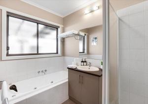 a bathroom with a tub and a sink and a shower at LIVING LUX Ballarat, Modern 2BR Home with Garden, Free Parking in Sebastopol +14 photos