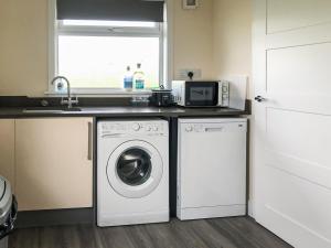 eine Küche mit Waschmaschine und Mikrowelle in der Unterkunft Ballygroggan Bungalow - Uk38174 in Machrihanish