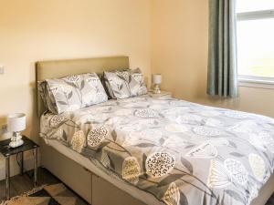 ein Schlafzimmer mit einem Bett mit einer weiß-grauen Bettdecke in der Unterkunft Ballygroggan Bungalow - Uk38174 in Machrihanish