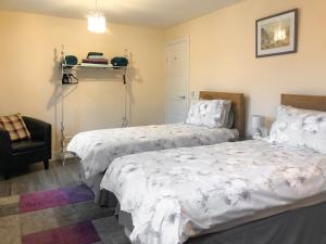 ein Schlafzimmer mit zwei Betten und einem Stuhl in der Unterkunft Ballygroggan Bungalow - Uk38174 in Machrihanish