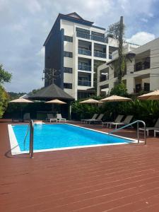 una piscina con sedie e ombrelloni accanto a un edificio di Spice & Sea Resort a Kata Beach