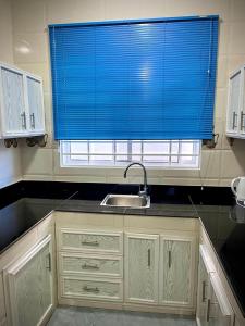 een keuken met een wastafel en een blauw raam bij Leo Home 1 in Nungwi