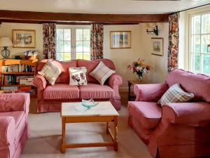 un soggiorno con 2 divani rosa e un tavolo di The Mansion Cottage a Tetford