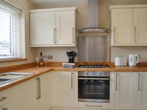 een keuken met witte kasten en een kookplaat oven bij Oceans 44 in Sewerby
