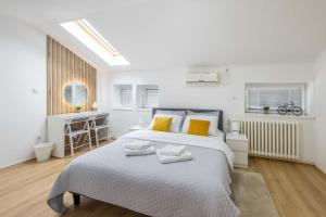 een witte slaapkamer met een groot bed met gele kussens bij Old City Rooms in Novi Sad