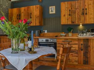 eine Küche mit einem Tisch mit einer Vase mit Blumen darauf in der Unterkunft Little Penquite in Landrake