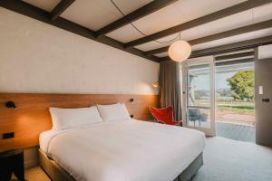 a bedroom with a large bed and a large window at The Black Dolphin Motel in Merimbula +48 photos