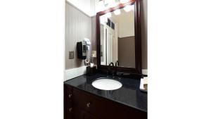 een badkamer met een wastafel en een spiegel bij Zane Grey - Historic Hotel in Cimarron