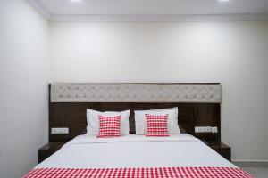 ein Schlafzimmer mit einem Bett mit roten und weißen Kissen in der Unterkunft Open Hotel by Olive - Hotel Siddartha Elite in Vijayawada