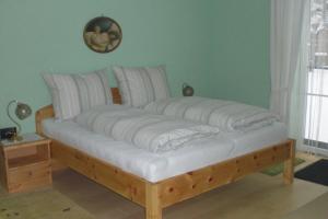 łóżko z białą pościelą i poduszkami w pokoju w obiekcie Ferienwohnung Szöky w mieście Bad Mitterndorf