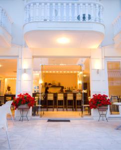 a dining room with red flowers in front of a building at Kalipso in Paralia Katerinis +42 photos