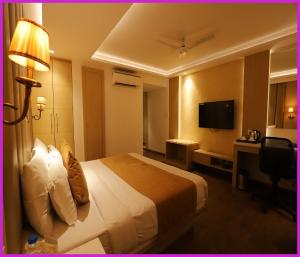 a hotel room with a bed and a television at PRIME LOCATION NEAR SEA BEACH HOTEL NILADREE WAVES! Puri - Near Jagannath Temple and Golden Beach- Swargadwar Beach - Bengali Market - A Top Rated Hotel IN PURI in Puri