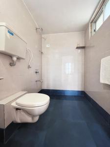 een badkamer met een wit toilet en een blauwe vloer bij Shlok Villa in Bāmangaon