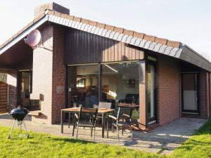 a house with a table and chairs and a grill at Ferienlandhaus Tossens in Butjadingen