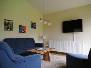 a living room with a blue couch and a table at Ferienlandhaus Tossens in Butjadingen +5 photos