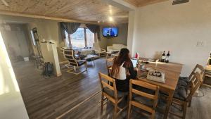 Eine Frau sitzt an einem Tisch in einem Wohnzimmer. in der Unterkunft The Bear Road in Churchill