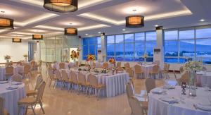 una sala banchetti con tavoli e sedie bianchi e finestre di Hotel St. Ellis a Legazpi