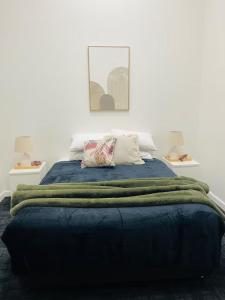 un letto con una coperta blu e due cuscini sopra di The Riverbank Suites, Central, New, Facilities a Collie