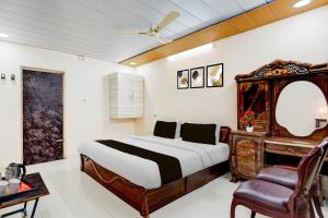 a bedroom with a bed and a desk and a mirror at Super Hotel O Chittoor Railway Station Formerly Four Oaks in Chittoor