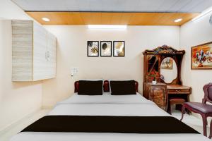 a bedroom with a bed and a desk and a mirror at Super Hotel O Chittoor Railway Station Formerly Four Oaks in Chittoor